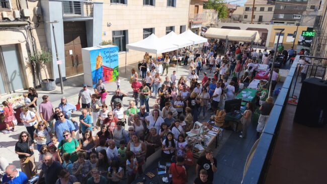 Vista panorámica del público y los puestos del V Mercadillo del Comercio Local en la Plaza de España de Zuera